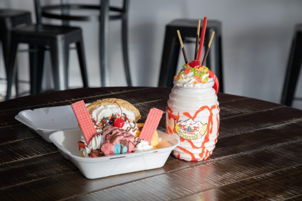 Ice cream in a to go container next to ice cream in a cup sitting on a table