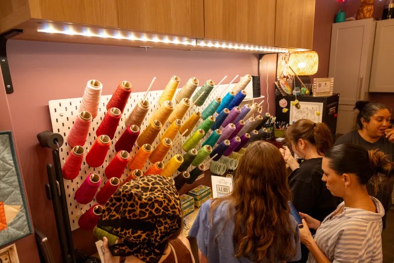 People standing in front of spools of colored yarn