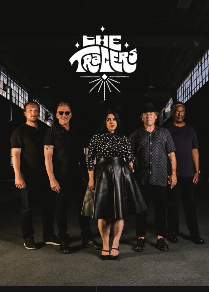 Photo of 5 members of a band standing side by side with a black background