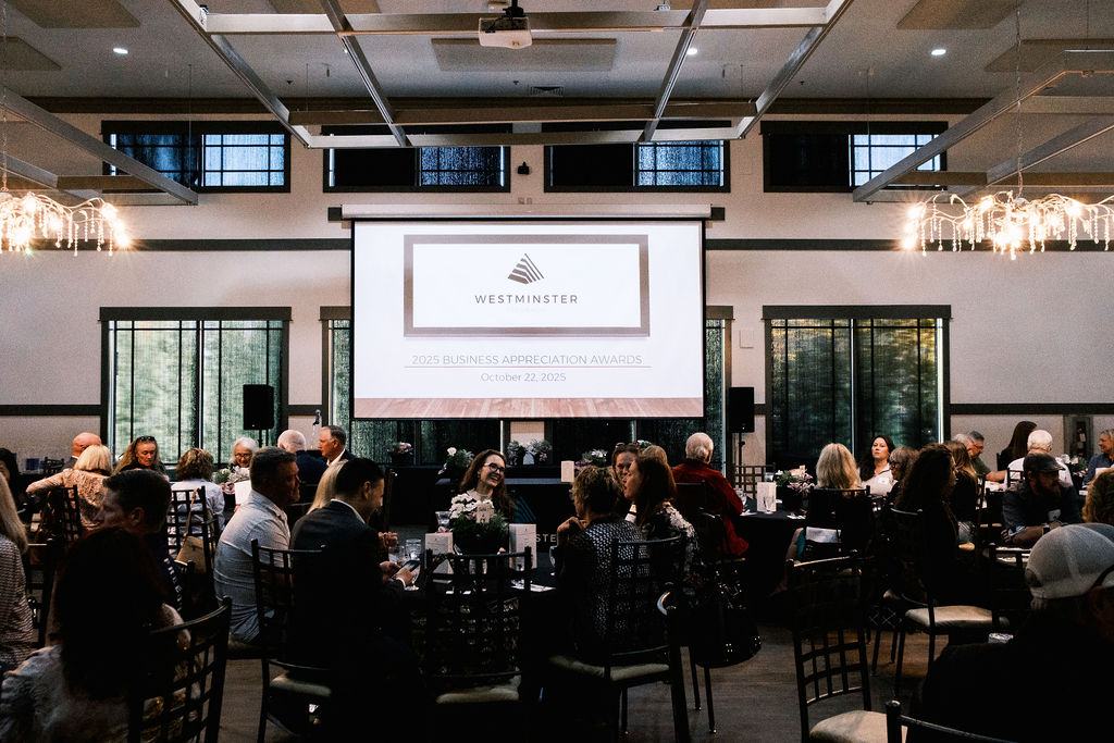 People sitting at tables in a large room with a projection screen at the front